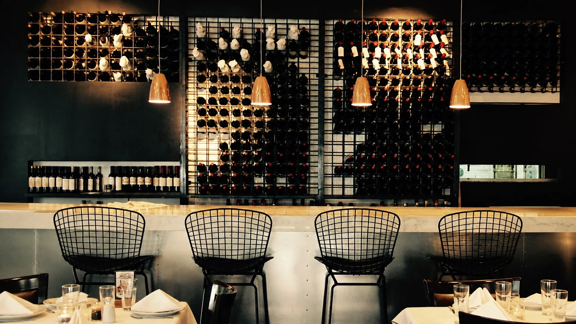 La barra de Ayerza con su pared de vinos y las mesas servidas